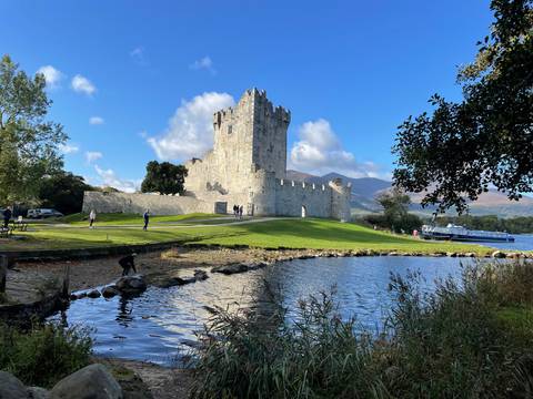       Castle by a serene lake with mountains in the background.
  