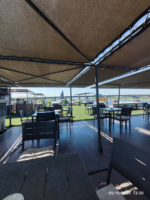       Outdoor dining area on a deck with views of a river and bridge.
  