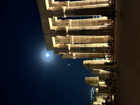 Night view of illuminated ancient ruins with a full moon.