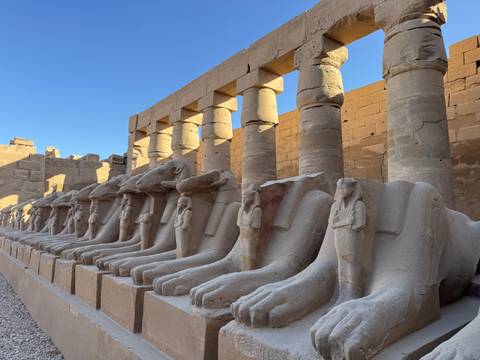 Row of stone statues in an ancient temple with blue sky background.
