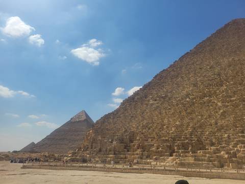 Two pyramids in Egypt against a blue sky with clouds.
