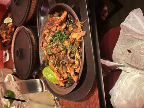 Sizzling plate of grilled food with vegetables on a table.