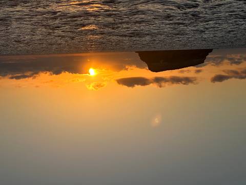 Ocean sunset with silhouetted island and beautiful sky.