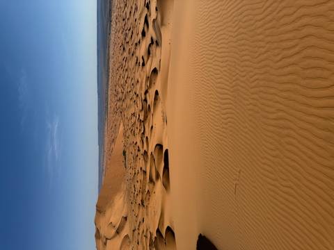Expansive view of sand dunes stretching out into the distance.