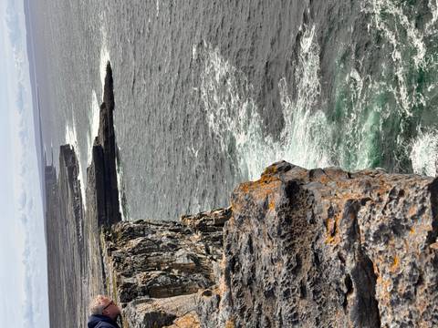       Rocky cliffs overlooking the ocean with waves crashing against them.
  