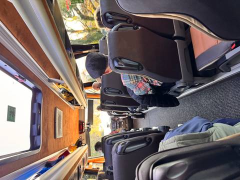       Interior of a minibus with passengers seated and looking out the window.
  