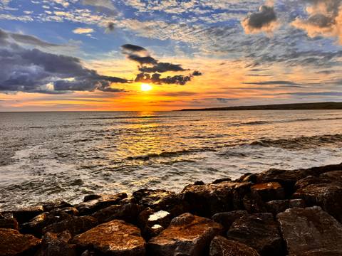       Sunset over the ocean with rocky shoreline
  