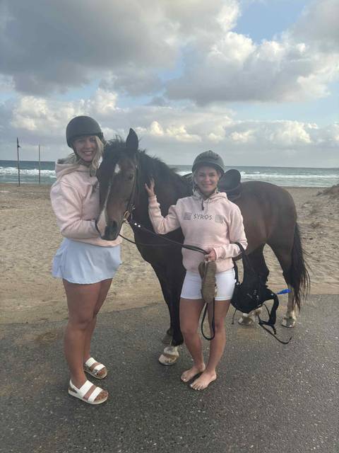      Two women with a horse on a beach
  