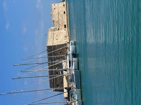       Sailboats in a harbor with a stone fort
  