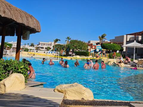       People enjoying a swimming pool in a resort setting.
  
