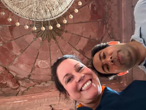 Smiling individuals inside a structure with an ornate ceiling.
