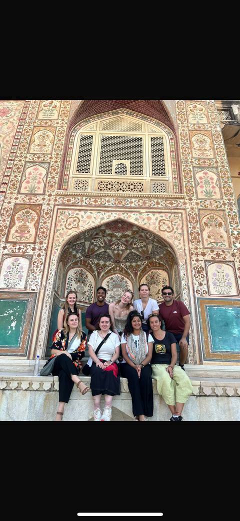 Group posing in front of a colorful ornate building wall.