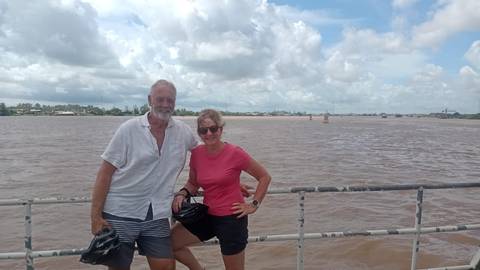 Two people standing by a metal railing with a river in the background.