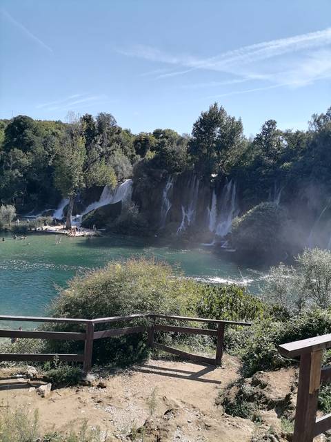       Wide view of a waterfall with lush surroundings.
  