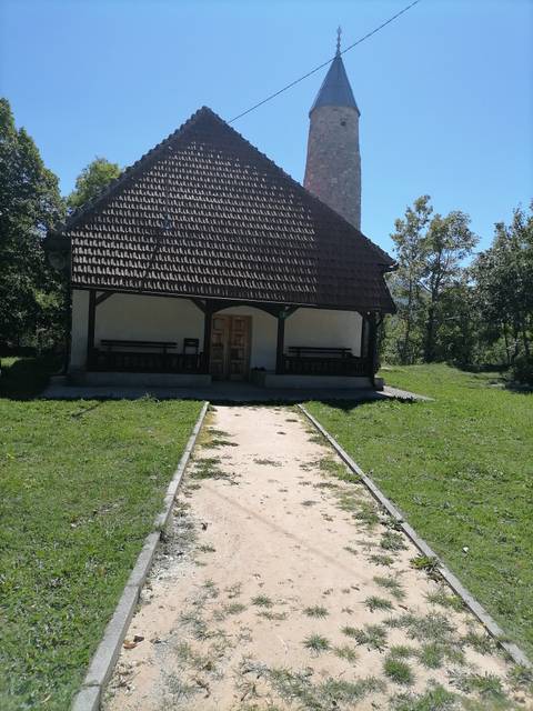       A small house with benches on the porch and grass lawn.
  