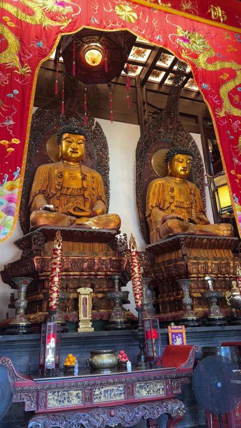       Two golden Buddha statues in a decorated temple.
  