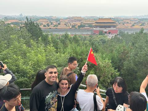       Group of tourists with a view of the Forbidden City from a hill.
  