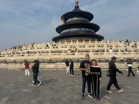       Two people posing in front of the Temple of Heaven.
  