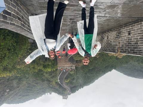       Two people in raincoats on the Great Wall of China.
  
