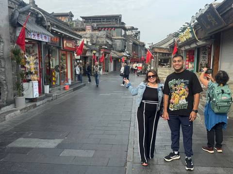       Couple posing in a traditional Chinese street with flags.
  