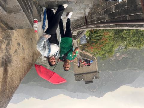       Couple posing with a red umbrella on the Great Wall of China.
  
