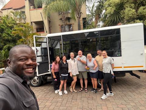 A group of people standing in front of a safari truck.