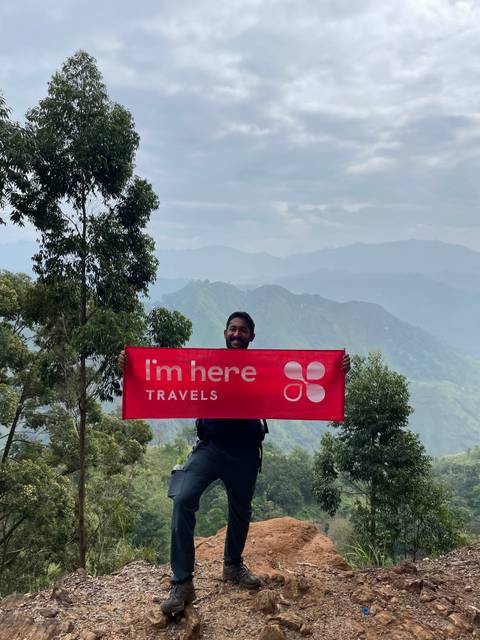 A person holding a branded banner in front of mountain scenery.