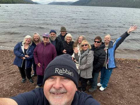 Group of people smiling by a lake's shore.
