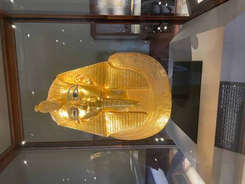 A golden ancient Egyptian artifact in a glass case.