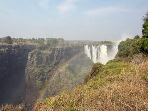       Waterfall with a rainbow forming across the gorge.
  