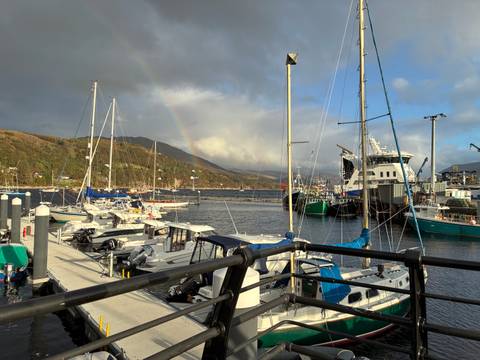       Harbor with boats and a rainbow in the sky.
  