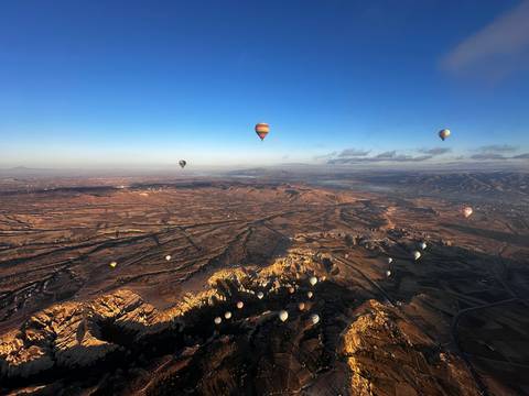       View of various hot air balloons over a vast landscape.
  