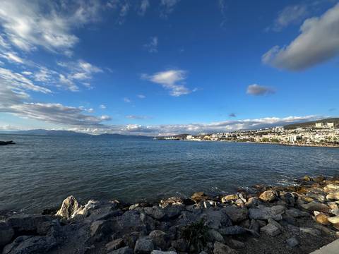       Coastal cityscape with a bay and mountains.
  
