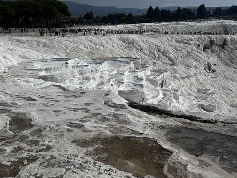       White travertine terraces with visitors.
  
