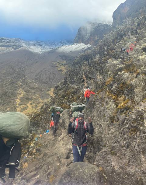 Hikers with backpacks climbing a rocky trail on a mountain.