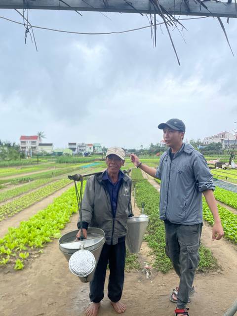       Two people standing in a fields with vegetables
  