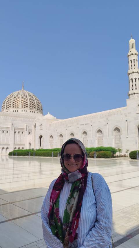       Person standing in front of a large mosque with a domed roof.
  
