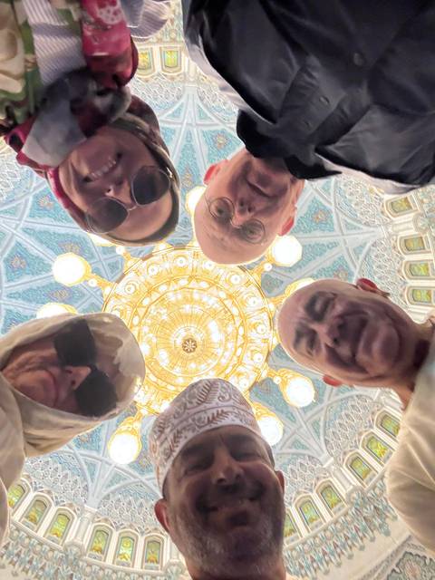       Group of people looking up at an ornate ceiling with a chandelier.
  