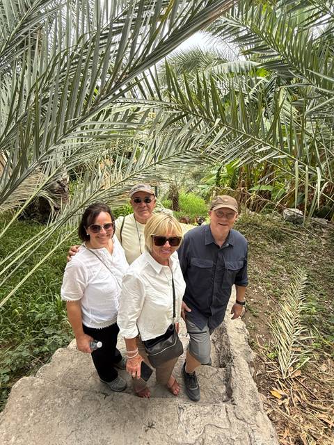       Group of four people posing among tropical plants.
  