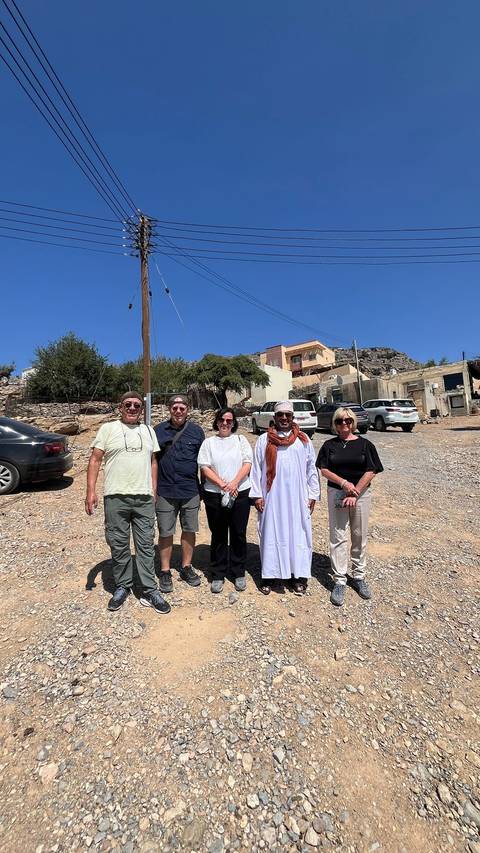       Five people posing outdoors under a clear blue sky.
  