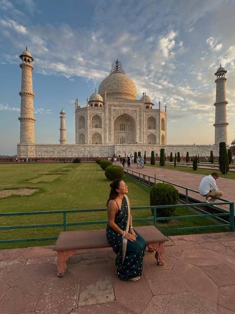 Taj Mahal with a person in the foreground, surrounded by gardens.