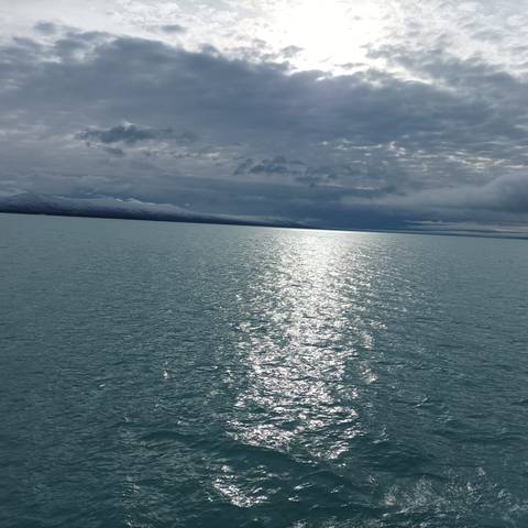 Expansive view of a calm lake with a mountain range in the distance.