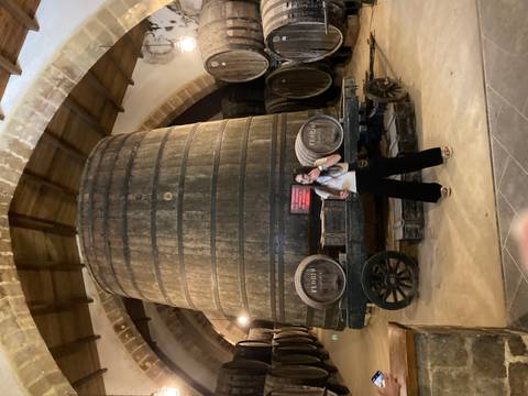 Person standing next to large wooden cask.