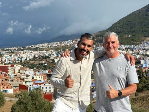 Two men posing with a cityscape in the background.