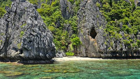       Dramatic karst cliffs by clear turquoise water.
  