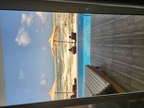 Beachside view from a resort with umbrellas and a pool overlooking the ocean.