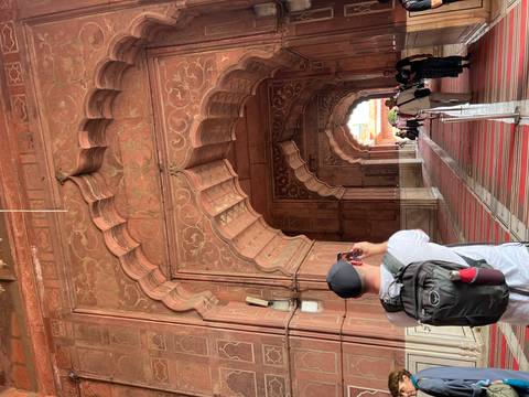 Tourist taking photos of intricate red sandstone architecture.