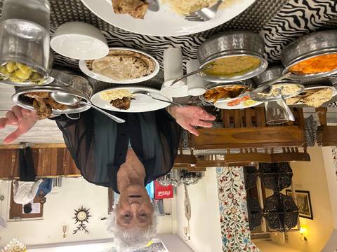 An elderly woman with a variety of dishes on the table.