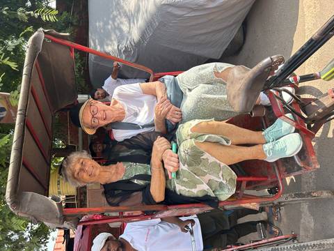       Two women sitting in a rickshaw, smiling.
  