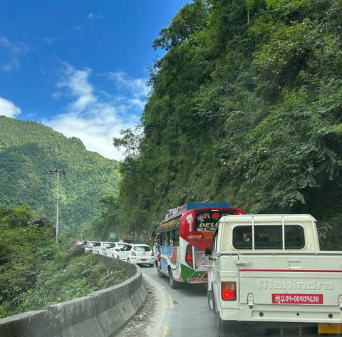 Cars and buses traveling on a road through forested hills.